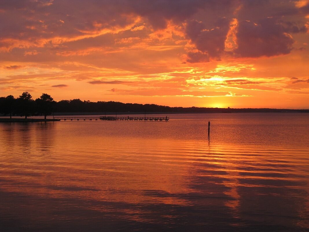Outdoor Activities in Mississippi 2026: River, Delta, and Gulf Ross Barnett Reservoir near Jackson Mississippi at sunset with golden sky reflected over open water and a fishing pier silhouette
