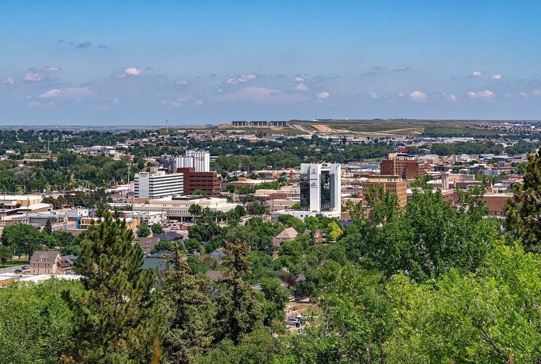 Cost of Living in South Dakota 2026: No Income Tax and Prairie Affordability Downtown Rapid City, South Dakota, seen from a hillside with the surrounding Black Hills behind