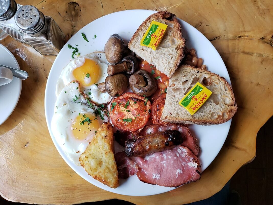 The Best British Food Experiences You Can’t Miss Full English breakfast with eggs bacon sausages beans toast and mushrooms, traditional British food 2024