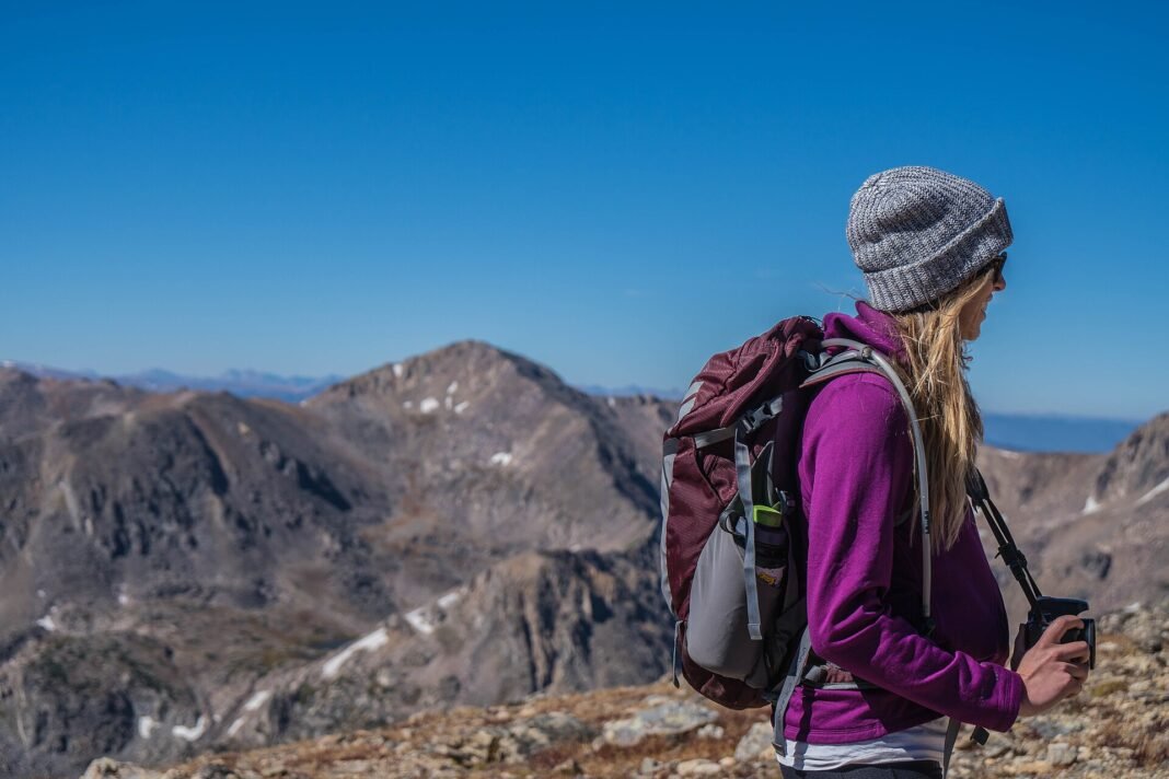 Solo Travel Safety Tips: How to Stay Safe and Confident on the Road Confident solo female traveler with backpack looking out over mountain landscape safe independent travel