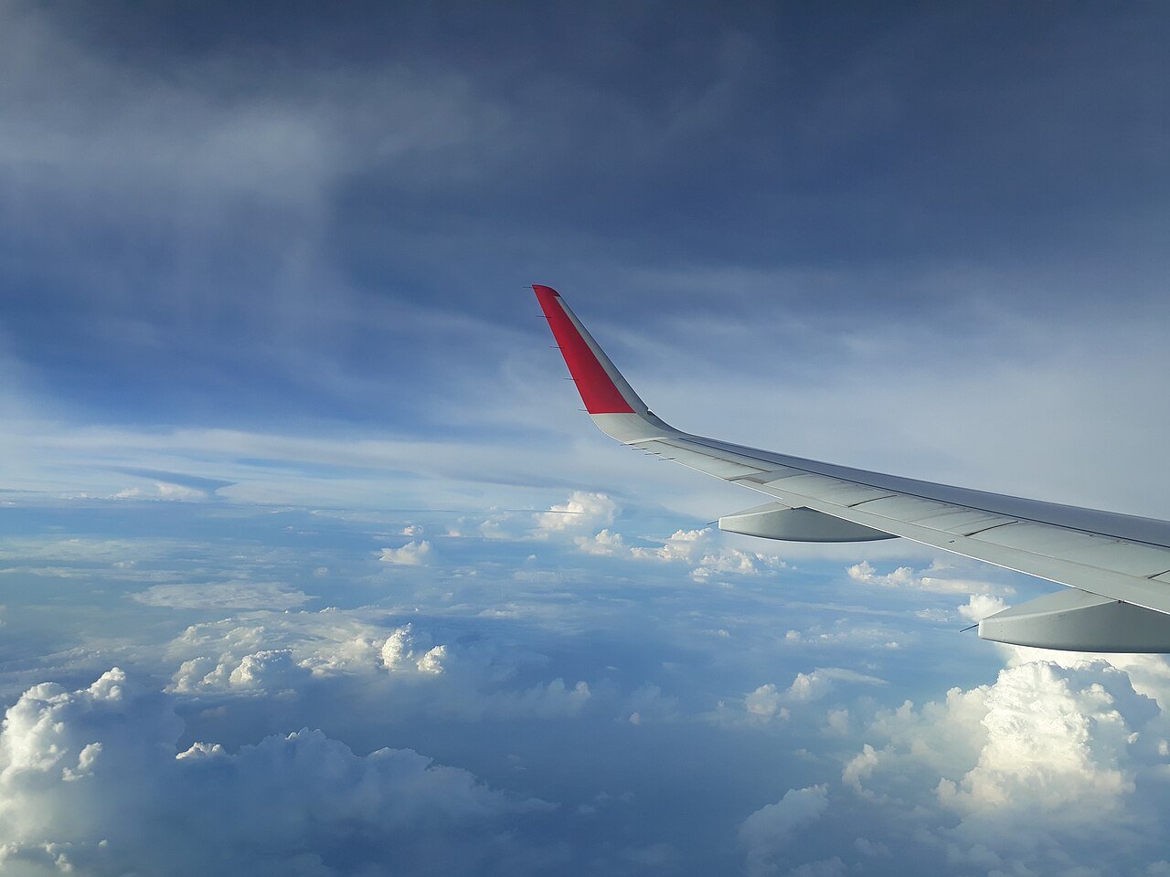 View from airplane window during flight — packing light enables carry-on only travel, eliminating checked baggage fees and the wait at baggage claim on arrival