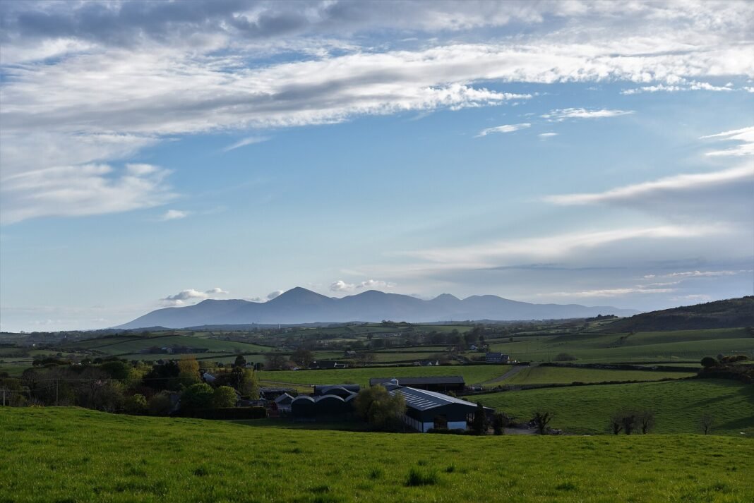 Northern Ireland Outdoor Guide 2026: Causeway Coast, Mourne Mountains, and Wild Atlantic Walks Mourne Mountains panorama rising behind County Down farmland Northern Ireland UK Slieve Donard