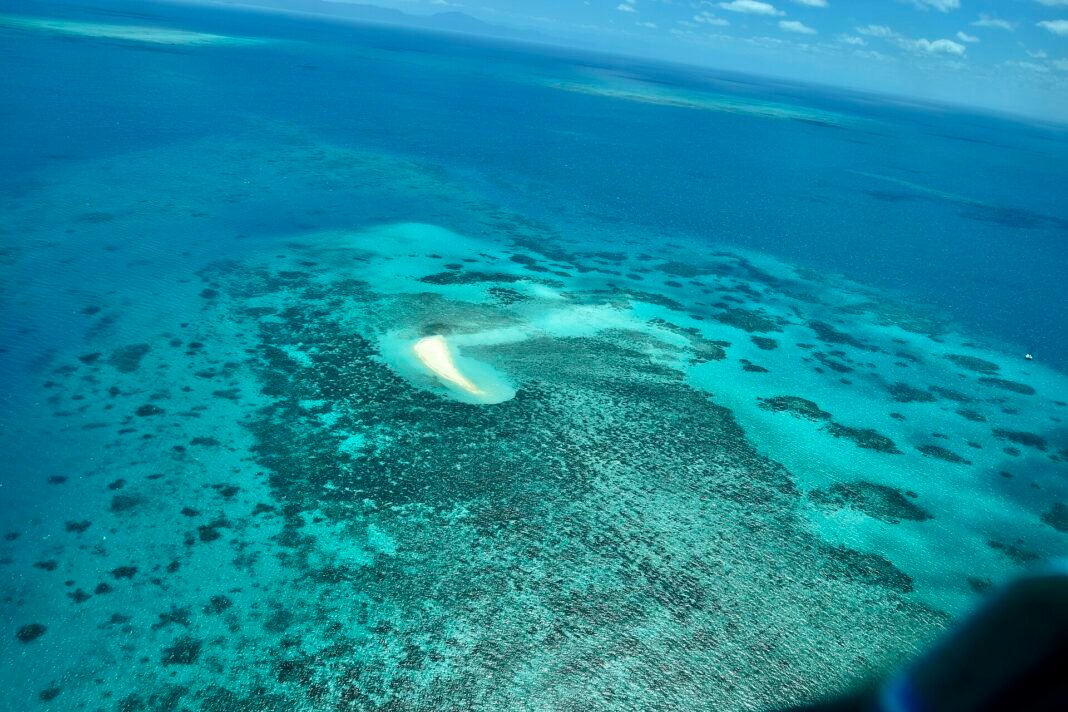 Queensland Travel Guide 2026: Great Barrier Reef, Tropical Rainforests, and the Gold Coast Aerial view of turquoise water and coral gardens surrounding a sand cay on the Great Barrier Reef, Queensland, Australia