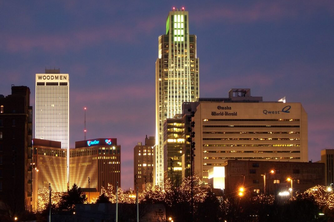 Cost of Living in Nebraska 2026: Midwest Value in America’s Heartland Downtown Omaha Nebraska skyline at night with First National Tower and Woodmen Tower lit at dusk