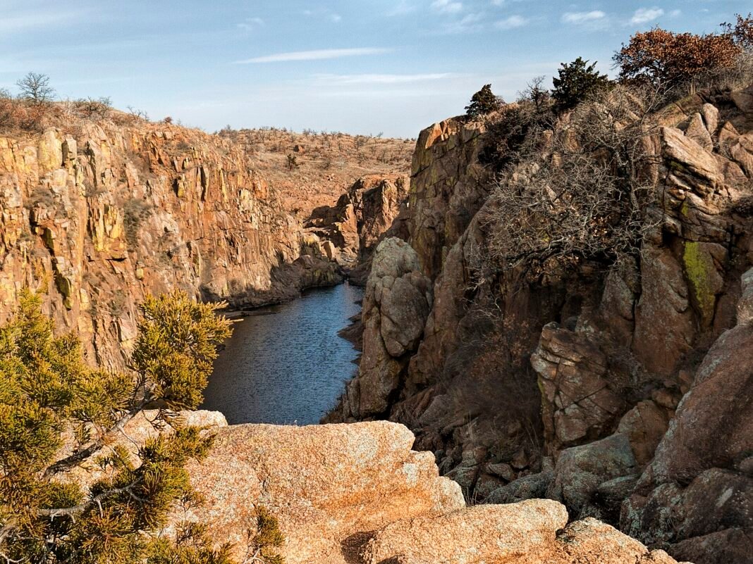 Outdoor Activities in Oklahoma 2026: Wichita Mountains, Red Rock Canyons, and the Tallgrass Prairie Wichita Mountains Wildlife Refuge Oklahoma granite rock canyon with clear creek and cedar under blue sky