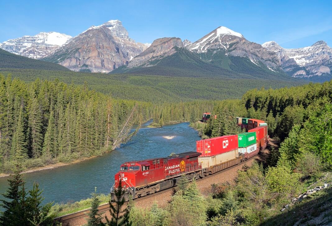 Canada Transportation Guide: Getting Around the World’s Second Largest Country Train rounding Morants Curve along the Bow River in Banff National Park with the Canadian Rockies behind, illustrating rail travel across Canada